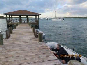 Randy holding on to the dingy dock at Hatchet Bay on a blustery day with Silver Maple in the distance 